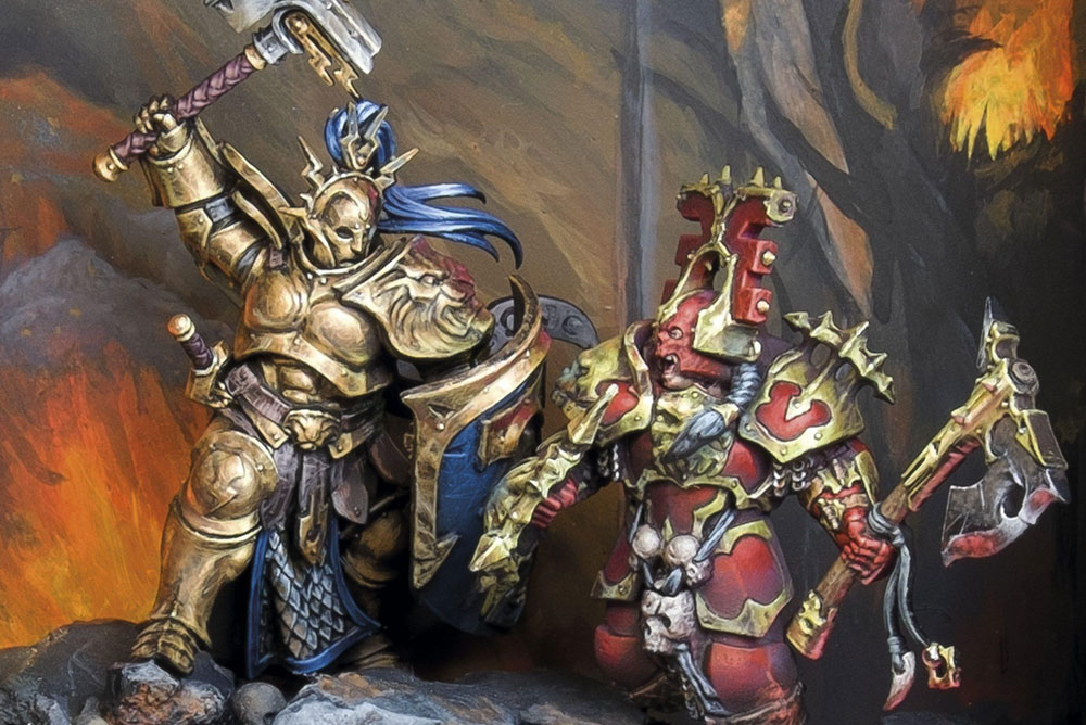 Diorama de Age of Sigmar representando un duelo entre un Stormcast Eternals dorado con martillo y un guerrero de Khorne con armadura roja. Miniaturas pintadas y fotografiadas por Kike Herrero sobre una base escénica detallada con calaveras, rocas y fondo de fuego.
