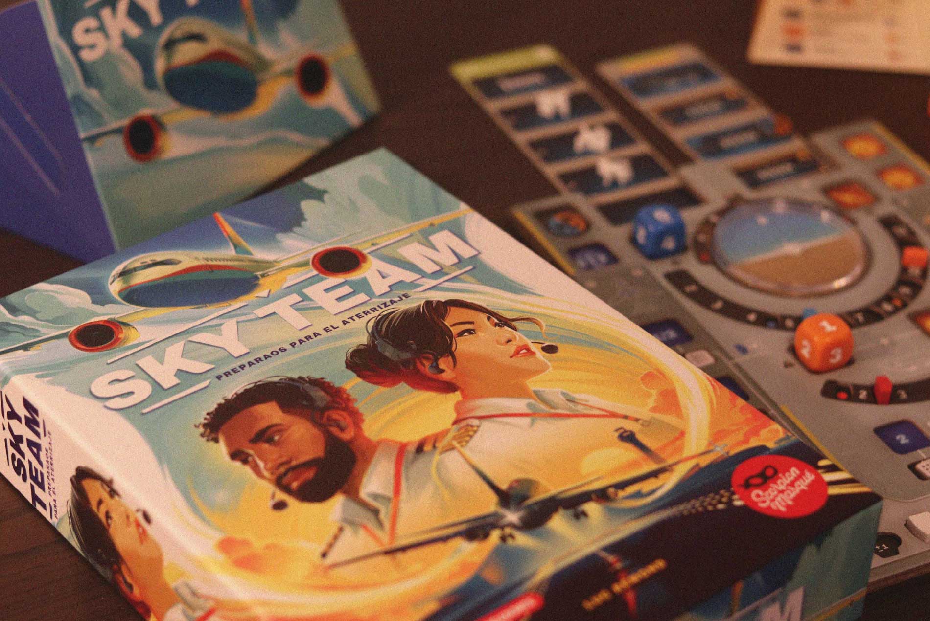 Caja de Sky Team y componentes del juego sobre la mesa, con dados y tablero de cabina aérea.