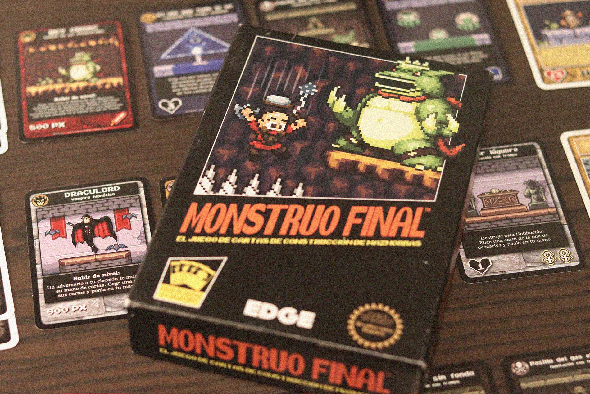 Caja del juego Monstruo Final con cartas de mazmorra y héroes desplegadas sobre la mesa