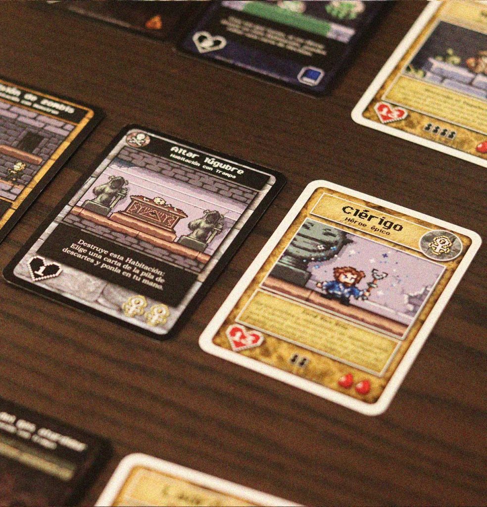 Cartas de Monstruo Final mostrando una habitación de mazmorra y un héroe épico enfrentados en mesa