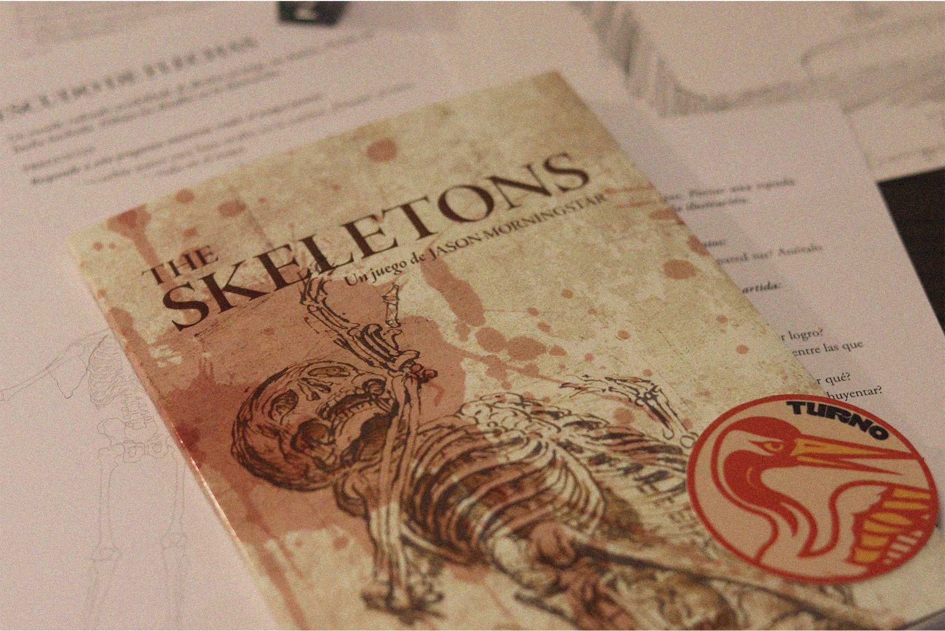 Portada del juego The Skeletons con dos esqueletos entrelazados sobre un fondo envejecido, marcada por manchas y desgaste.