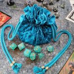 saquito de dados artesanal azul de Costurero Rolero sobre mesa de juego de rol con dados y cartas