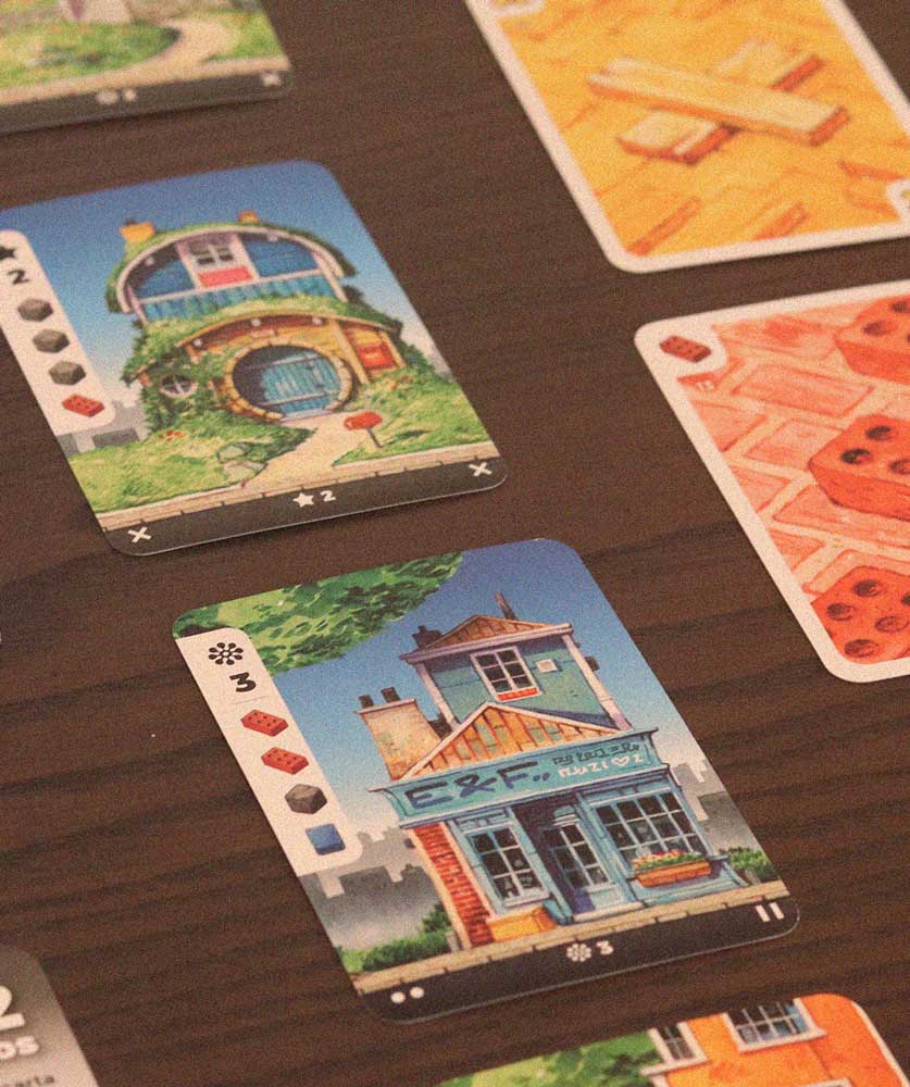 Cartas de Barrio con materiales y casas dispuestas en mesa durante la partida