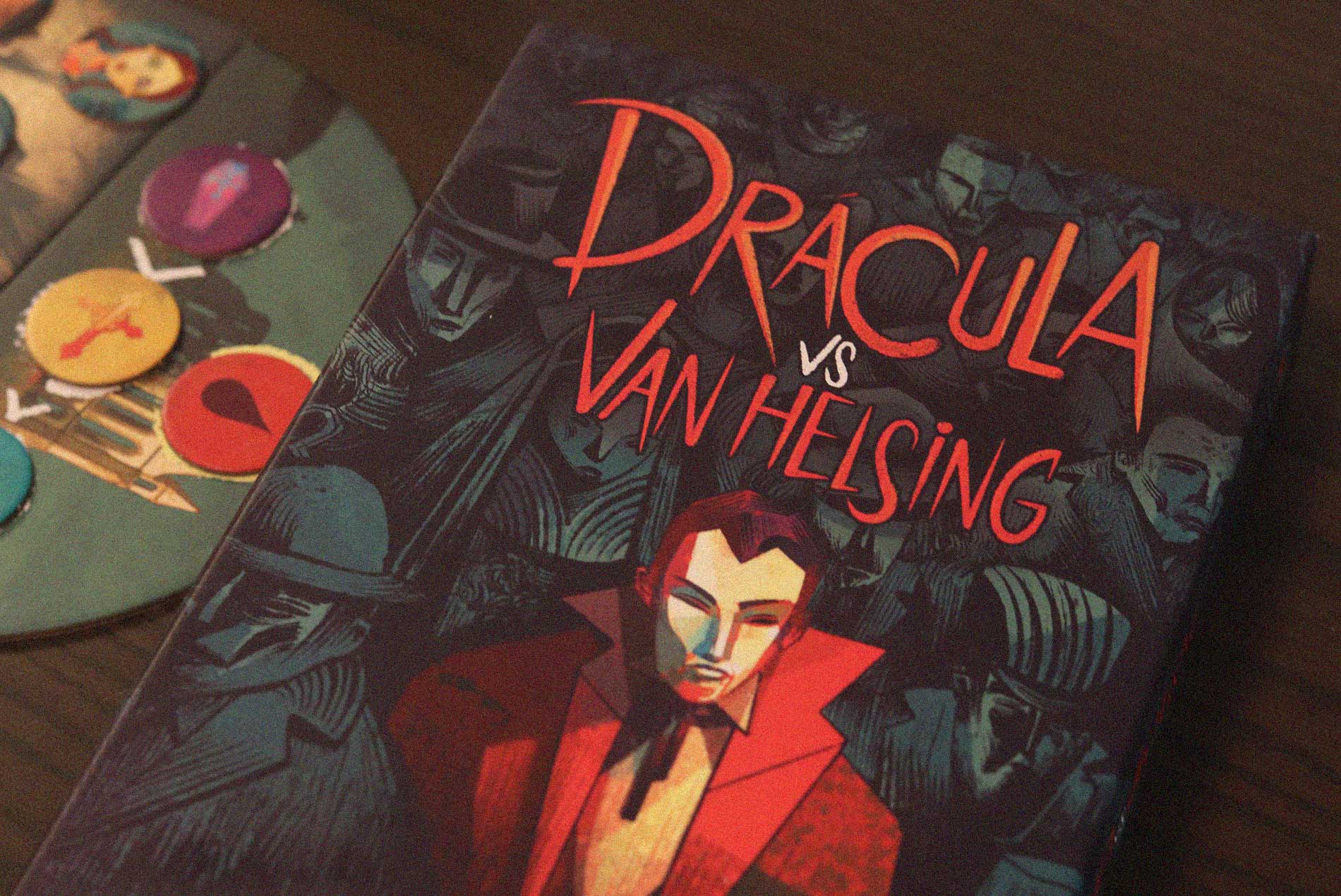 Caja de Drácula vs Van Helsing sobre una mesa junto al tablero y fichas de colores durante una partida.