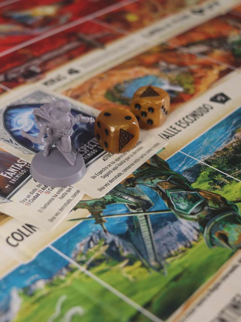 Miniatura de personaje, dados y cartas sobre el tablero de Talismán 5.ª edición durante una partida.