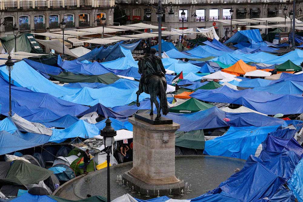 Vista de una plaza ocupada por numerosas tiendas de campaña de distintos colores alrededor de una estatua ecuestre.
