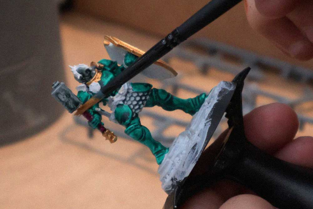Participante pintando una miniatura de fantasía con un pincel durante una actividad de pintura en Freak Festival.