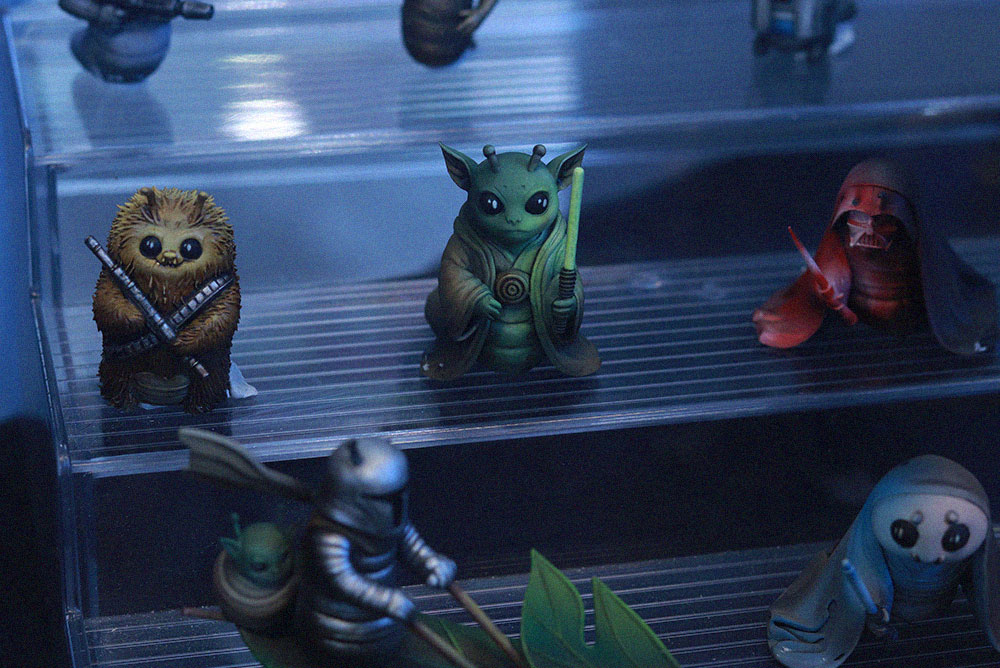 Miniaturas pintadas de personajes de Star Wars, con figuras de Grogu, Chewbacca y Darth Vader, expuestas en una vitrina.