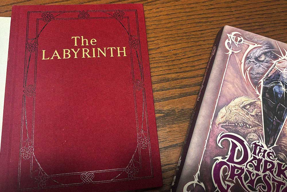 Libros de los juegos de rol de Dentro del Laberinto y The Dark Crystal sobre una mesa de madera.