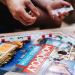 Personas jugando al Monopoly, con el tablero, las cartas y los dados sobre la mesa.