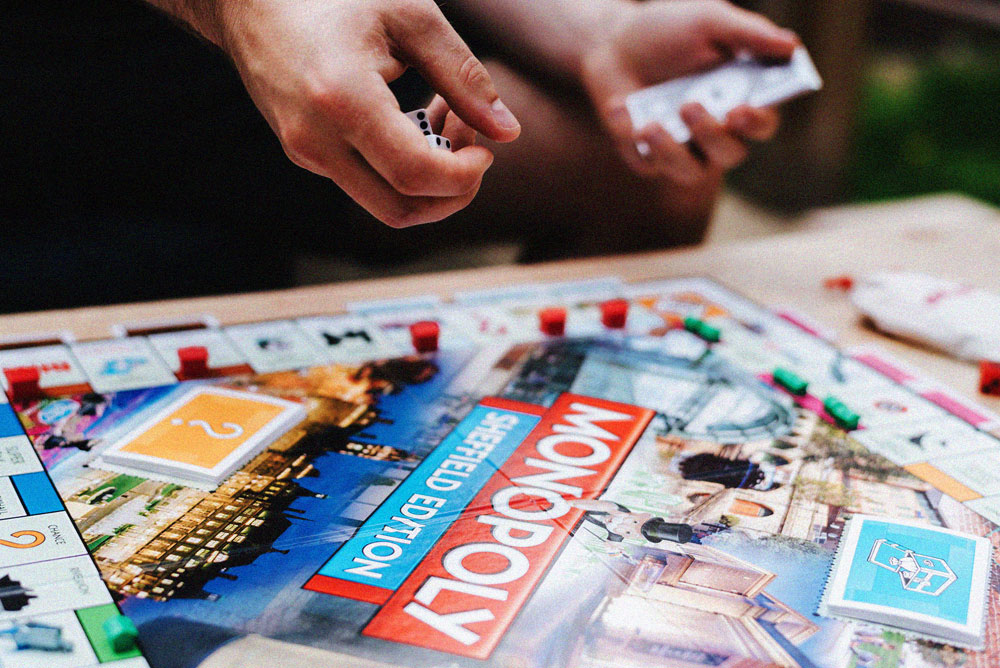 Personas jugando al Monopoly, con el tablero, las cartas y los dados sobre la mesa.
