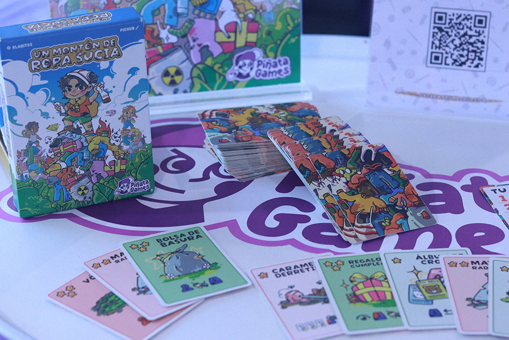 Juego de cartas Un montón de ropa sucia de Piñata Games, con la caja y varias cartas desplegadas sobre la mesa en Freak Wars 2026.